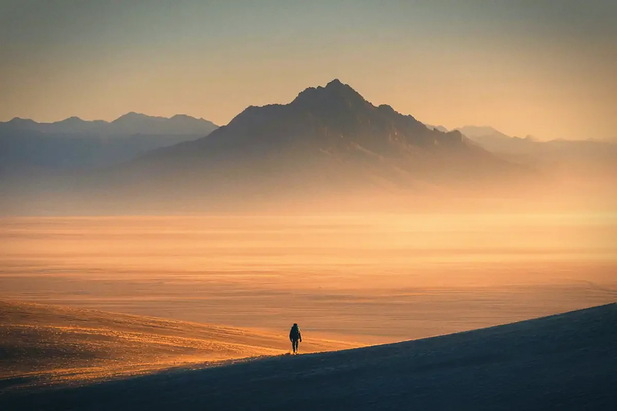 A lone figure walking a dune ridge at dusk